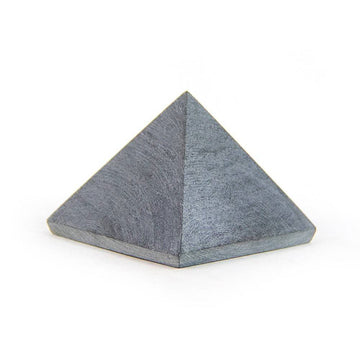 Unpolished soapstone pyramid on white background, angled view showing natural texture and soft tones.